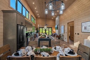 Une cuisine spacieuse dotée d’un îlot central, de murs en bois et de grandes fenêtres.