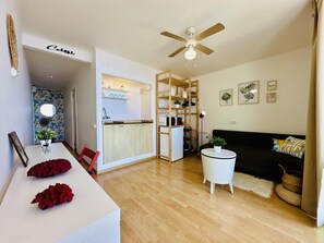 Un espacio habitable compacto con kitchenette, comedor, sofá y ventilador de techo.