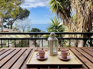 A wooden table with two pink cups and a white bottle on a tray, overlooking a scenic view with trees and a clear sky. - Gigi Loft CostaBravaSi - Sea views, beach (Santa Cristina d'Aro)