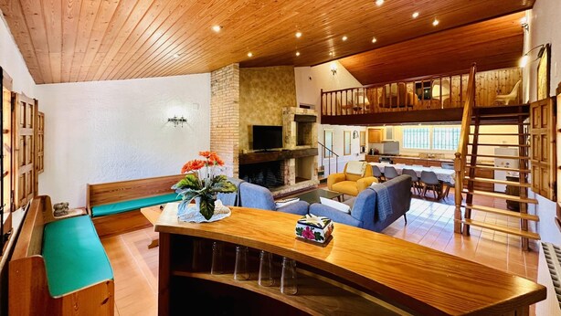 A cozy living room with wooden ceiling, a fireplace, a dining area, and a loft space. - Calma CostaBravaSi - Terrace, garden, Barbecue (Santa Cristina d'Aro)