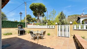 An outdoor patio with a grill, a table with chairs, and a white fence. - Calma CostaBravaSi - Terrace, garden, Barbecue (Santa Cristina d'Aro)