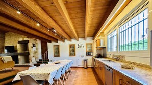 A spacious kitchen with a long dining table, wooden cabinets, and large windows. - Calma CostaBravaSi - Terrace, garden, Barbecue (Santa Cristina d'Aro)