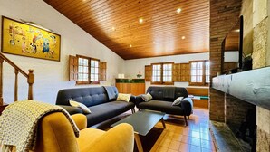 A spacious living area with a wooden ceiling, a sofa set, a dining table, and a fireplace. - Calma CostaBravaSi - Terrace, garden, Barbecue (Santa Cristina d'Aro)