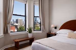 Ein Schlafzimmer mit Bett, Nachttisch, Lampe, Bank und einer Topfpflanze.