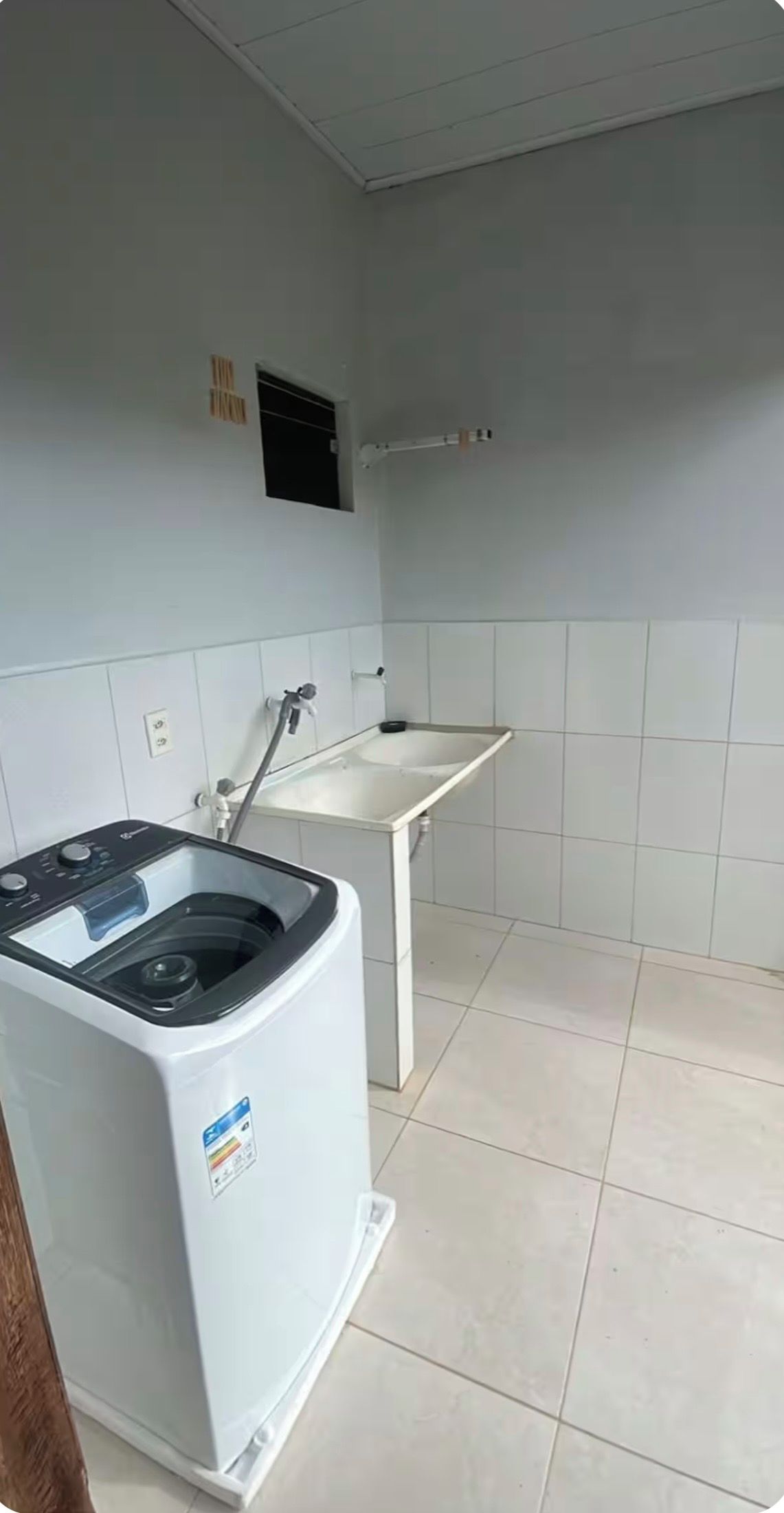 A compact kitchen with a built-in washing machine, a sink, and a small window.