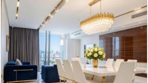 Un espace de salle à manger moderne avec une table ronde, des chaises blanches et un lustre.