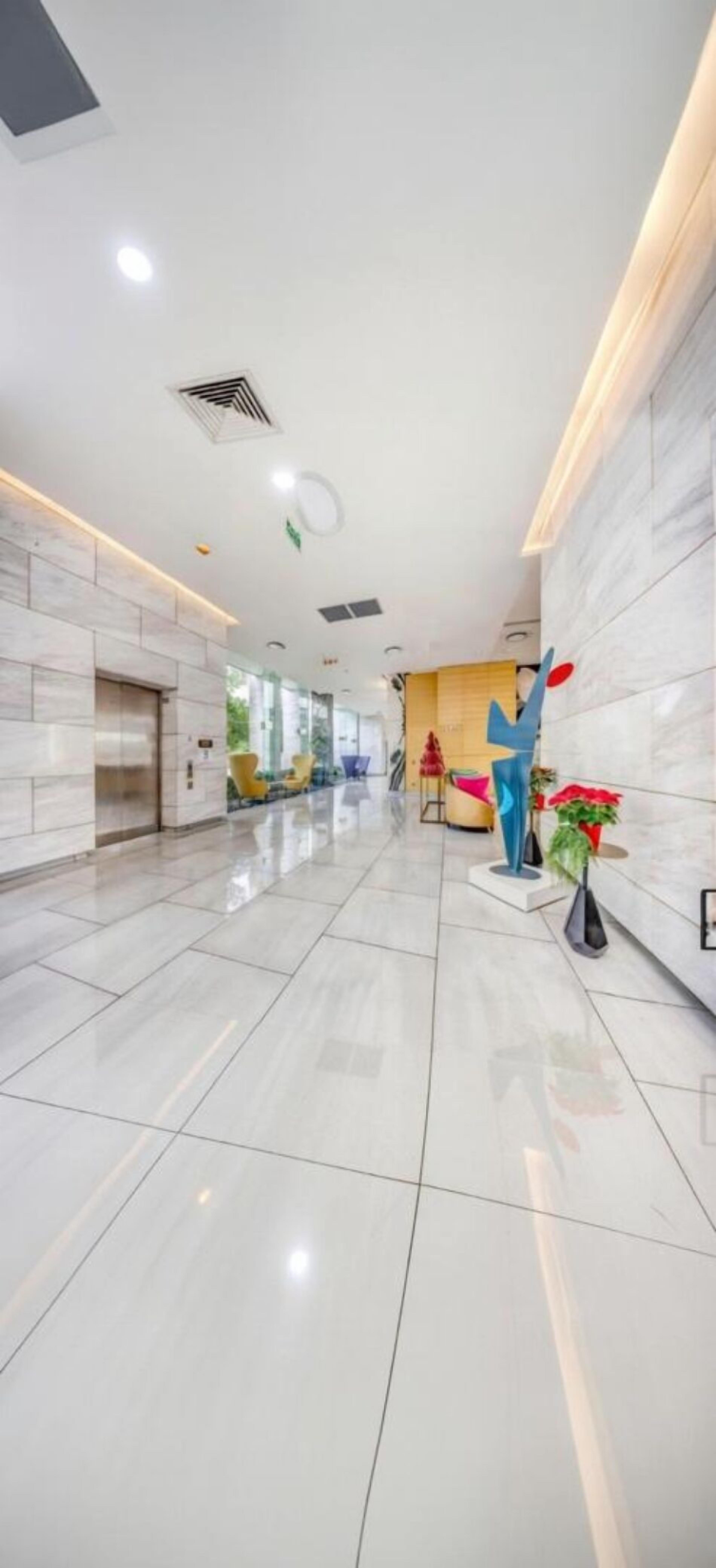 Eine geräumige Lobby mit hoher Decke, einer zentralen Treppe und einem modernen Empfangsschalter.