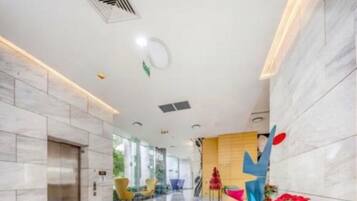 Eine geräumige Lobby mit hoher Decke, einer zentralen Treppe und einem modernen Empfangsschalter.