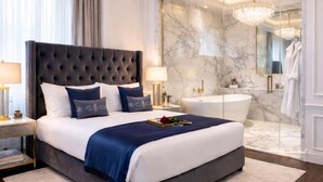 Une chambre moderne avec un grand lit, un mur en marbre et un lustre.