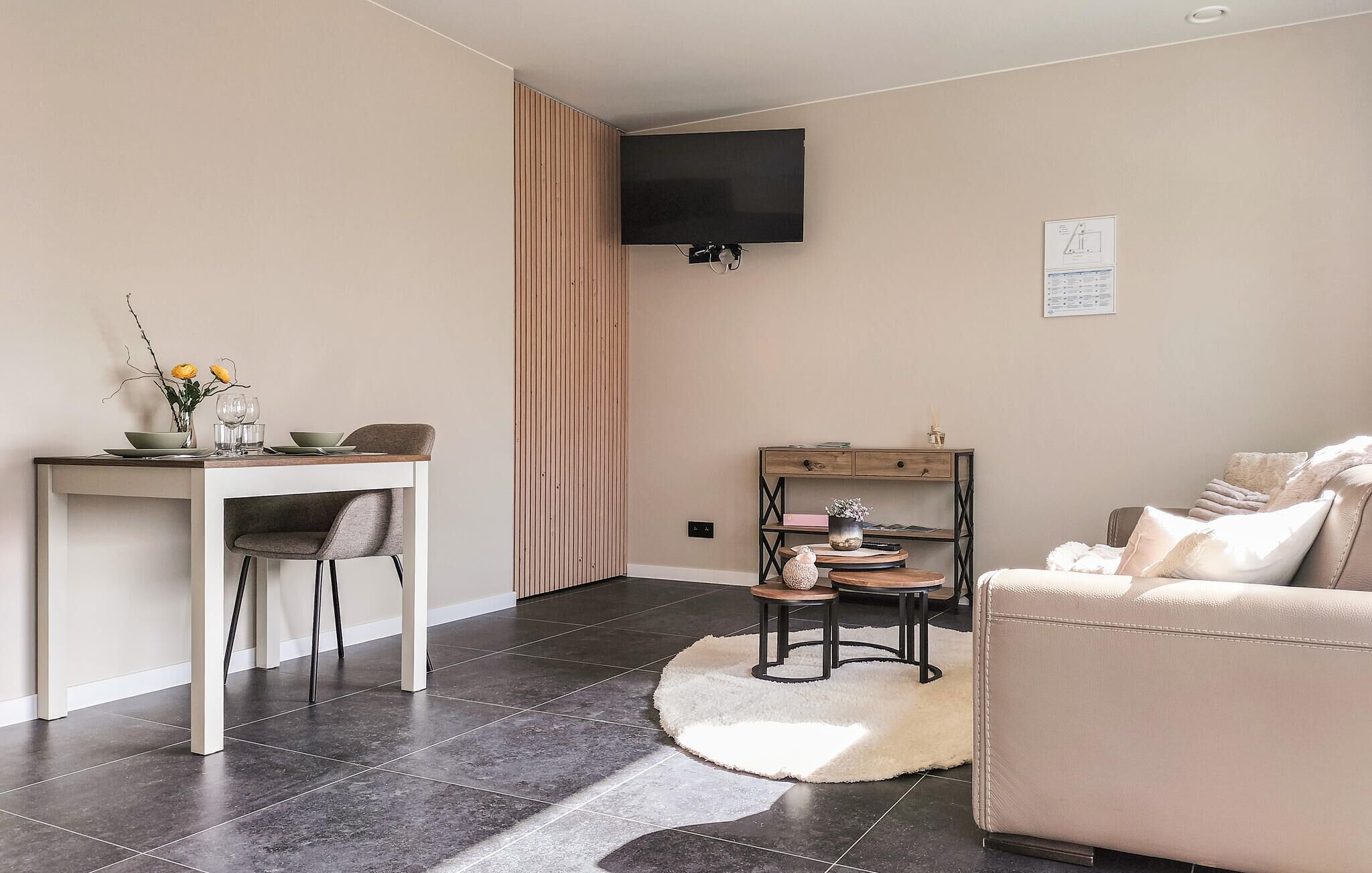 Una sala de estar moderna con comedor, un televisor de pantalla plana en la pared y un sofá acogedor.