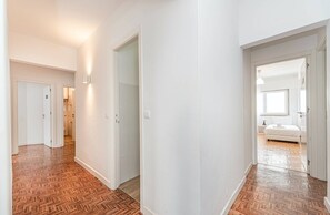 A hallway with wooden flooring leading to a bedroom with a bed and a nightstand. - HOUZE Spacious Apartment near Marquês de Pombal (Lisboa)