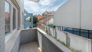 Un balcón con suelo de baldosas, una reja metálica y vista a edificios y una masa de agua.