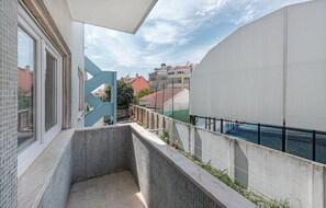 A balcony with a tiled floor, a metal gate, and a view of buildings and a body of water. - HOUZE Spacious Apartment near Marquês de Pombal (Lisboa)