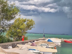 A marina with boats docked, a person standing by the water, and a cloudy sky. - Il Mio Lago - One Bedroom Apartment, Sleeps 4 (Desenzano del Garda)