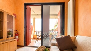 Una sala moderna con un sofá, un mueble bajo y un ventanal corredizo que da a un espacio exterior.