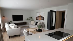 Una sala de estar moderna con sofá, mesa de centro y una isla de cocina con estufa integrada.