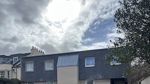 Un edificio residencial con entrada para vehículos, una furgoneta blanca estacionada y un automóvil.