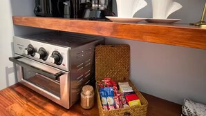Uma cozinha com fogão, cafeteira e um cesto de cápsulas de café.
