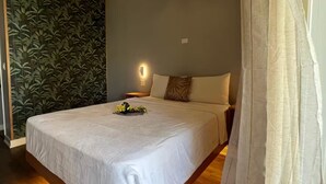 Quarto com cama, ar-condicionado fixado na parede, luminária de teto e parede com padrão de folhagem.