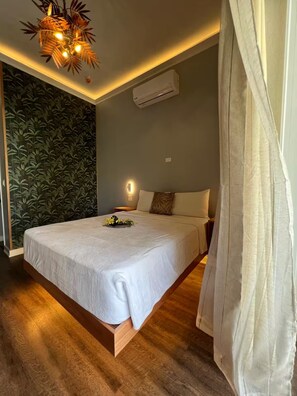 Ein Schlafzimmer mit einem Bett, einer Wand-Klimaanlage, einer Deckenleuchte und einer Wand mit einem Blattmuster.