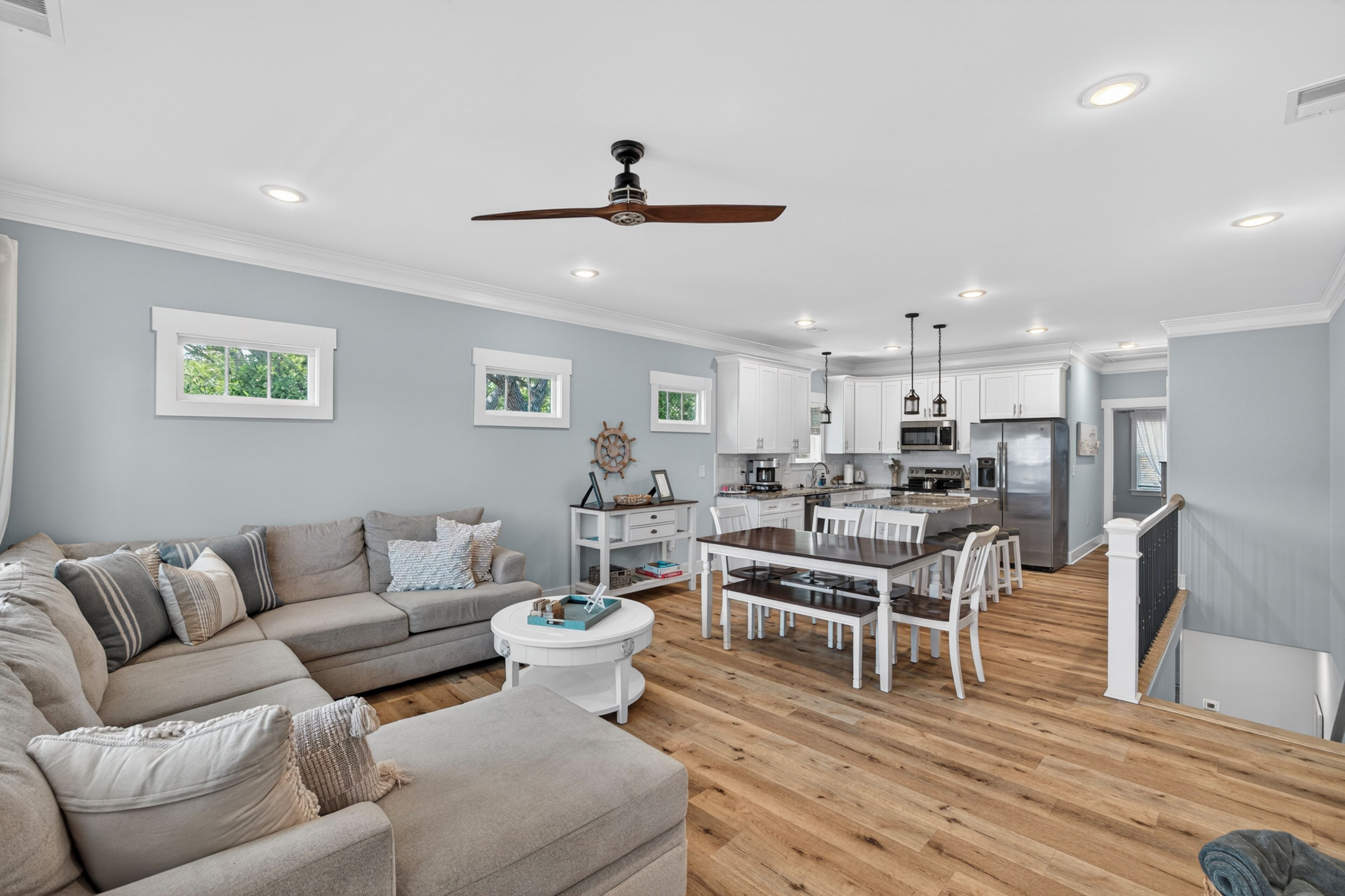 A modern living room with a sofa, dining table, and kitchen area.