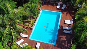 An aerial view of a swimming pool surrounded by palm trees and lounge chairs.