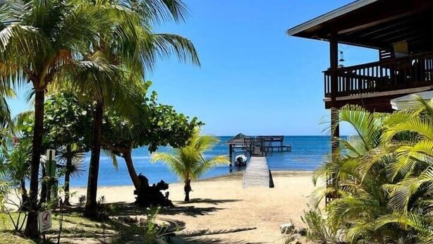 A beach path leading to a wooden building with a dock extending into the water.
