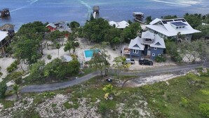 A coastal property with a swimming pool, a house with solar panels, and a view of the ocean. - Milton 2 Br Quiet Beachfront Pool Dock (José Santos Guardiola)