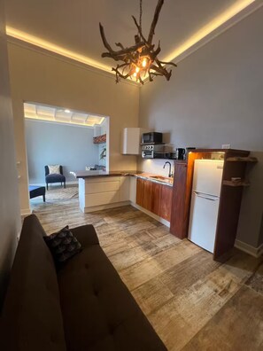 A compact kitchen with a built-in oven, microwave, and refrigerator. A unique chandelier hangs above the counter. - #3, King Bed Beach 1min St. Lawrence Gap ‘Relax’ (Oistins)