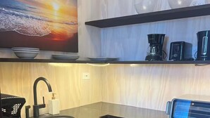 Une cuisine moderne avec un plan de travail noir, un évier et une machine à café.