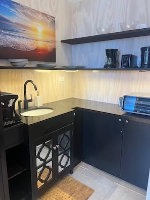 Eine moderne Küche mit schwarzer Arbeitsplatte, einem Spülbecken und einer Kaffeemaschine.