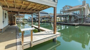 A waterfront property with a wooden dock, a covered area, and a house with a balcony. - Spacious 4-bedroom house in lovely Jamaica Beach with AC (Jamaica Beach)