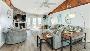 A living room with a fireplace, a sofa, a coffee table, and a television. - Spacious 4-bedroom house in lovely Jamaica Beach with AC (Jamaica Beach)