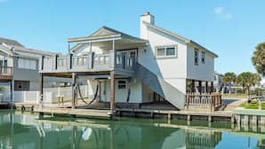 A waterfront house with a covered deck and a dock extending into the water. - Spacious 4-bedroom house in lovely Jamaica Beach with AC (Jamaica Beach)