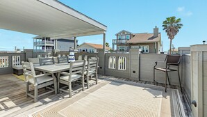 An outdoor patio with a covered seating area, a table, and chairs. - Spacious 4-bedroom house in lovely Jamaica Beach with AC (Jamaica Beach)