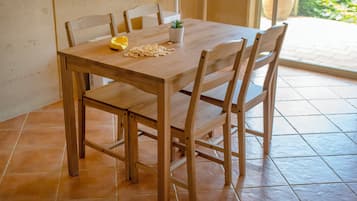 A wooden dining table with four chairs, a potted plant, and a yellow object on the table.