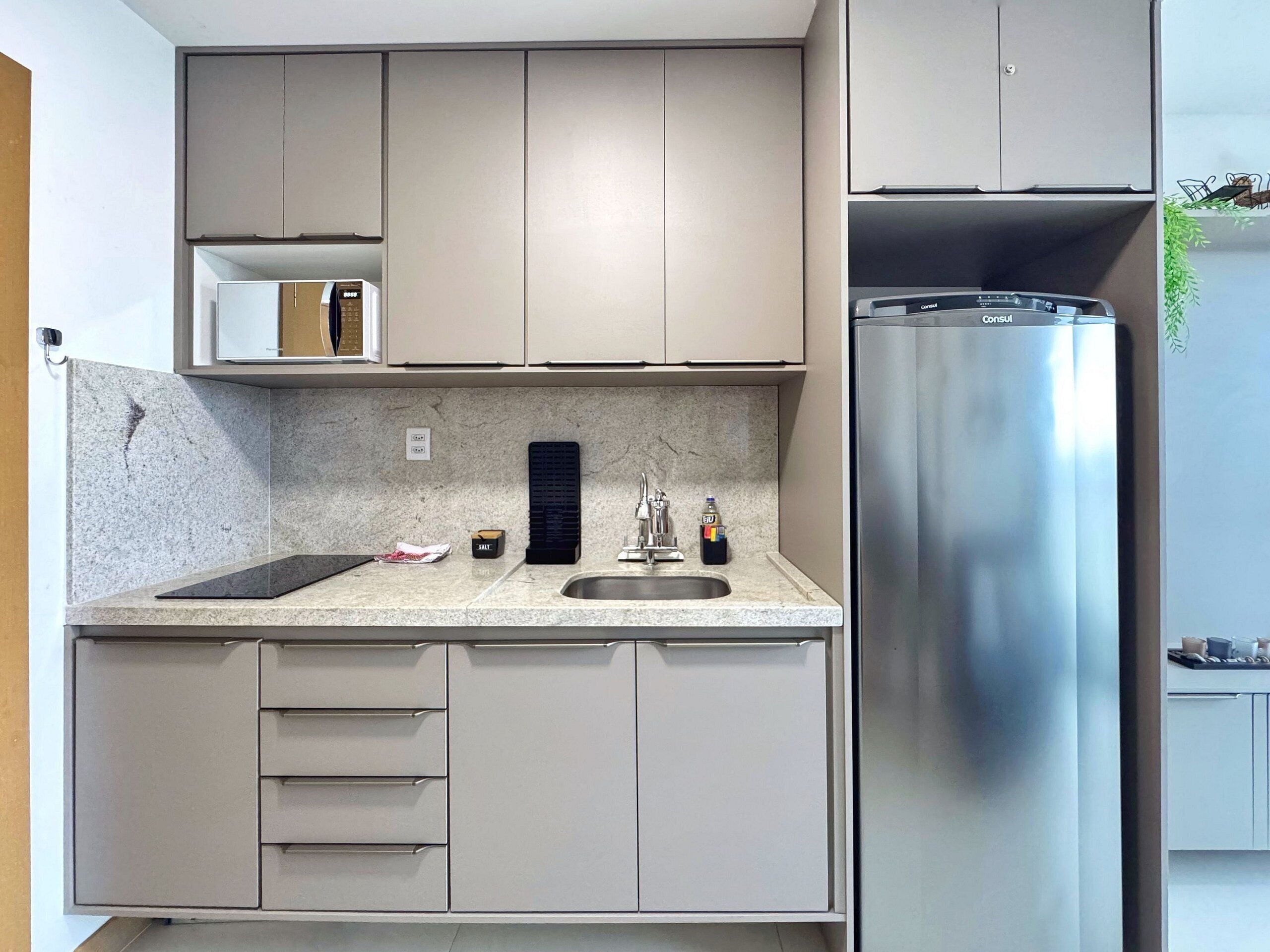 Una cocina moderna con un refrigerador de acero inoxidable, horno empotrado y encimera de granito.