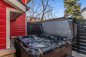 A hot tub with a cover, a red building, and a wooden fence. - 1150 Park Ave (Park City)