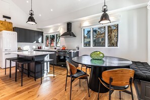 A modern kitchen with a central island, black chairs, and a round dining table. - 1150 Park Ave (Park City)