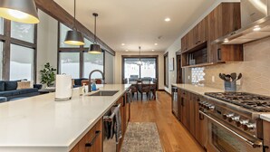 A modern kitchen with a large island, stainless steel appliances, wooden cabinets, and pendant lighting. - Plum Creek Lodge • Expansive Mountain Views • 6BR • 5.5BA • Game Room (Cle Elum)