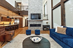 Un salon moderne avec une cheminée, un canapé bleu et un coin repas doté de meubles en bois.