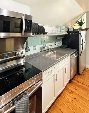 A modern kitchen with stainless steel appliances, a granite countertop, and white cabinetry.