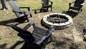 A fire pit surrounded by Adirondack chairs in a grassy outdoor area. - Mountain-View 3BR Home w/ Firepit • Hatfield AR (Hatfield)