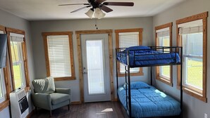 A room with a bunk bed, a ceiling fan, a window with blinds, a chair, and a heater. - Mountain-View 3BR Home w/ Firepit • Hatfield AR (Hatfield)