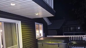 A deck with a hot tub, a covered patio, and a house with a balcony. - Grand Marais Retreat *Hot tub* (Grand Marais)