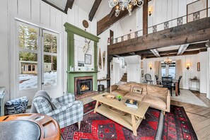 A cozy living room with a fireplace, a sofa, and a coffee table. - Olympic Valley Escape - Riverside Views + Hot Tub (Tahoe City)
