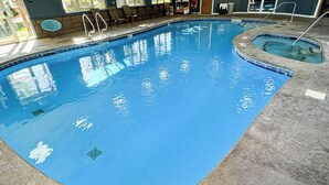An indoor swimming pool with clear water, a diving board, and lounge chairs. - Studio 6 Lake George, NY - Adirondacks (Lake George)