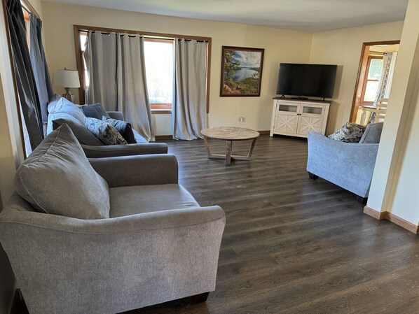 A living room with two sofas, a coffee table, a TV, and a painting on the wall.