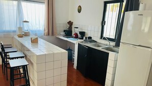 A kitchen with white tiles, a black countertop, a refrigerator, and a sink. - Cocoa department, unbeatable location. (puerto escondido)