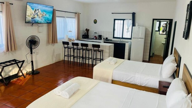 A hotel room with two beds, a kitchenette, a dining area, and a TV on the wall. - Cocoa department, unbeatable location. (puerto escondido)